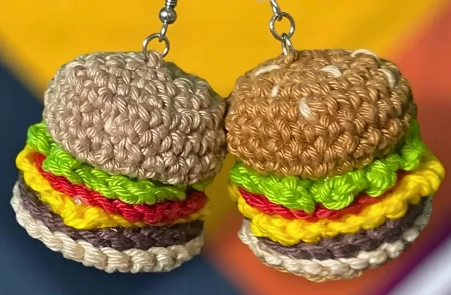 Chaveiro Mini Hambúrguer Amigurumi Receita passo a passo em crochê com fios coloridos ao fundo, ideal como lembrancinha artesanal criativa.